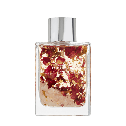 A glass bottle of WILD ROSE FACE & BODY OIL, elegantly displayed with rose petals and buds inside it, showcasing its luxurious formula and natural ingredients. 